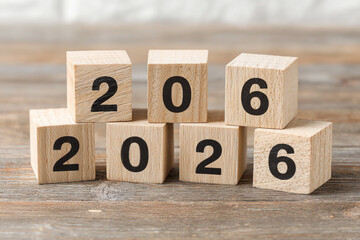 Wooden cubes form the number 2026 on a rustic wood surface heralding the new year
