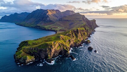 Dramatic aerial perspective showcases a rugged island coastline featuring cliffs, rolling hills, and deep blue sea under a partly cloudy sky during sunset, creating a scenic panorama.