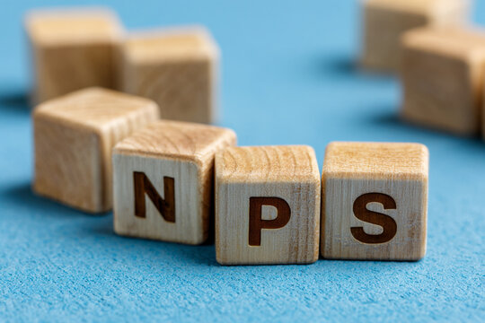 Wooden letter blocks spelling the acronym NPS on a blue surface representing the Net Promoter Score a metric used to gauge customer satisfaction and loyalty