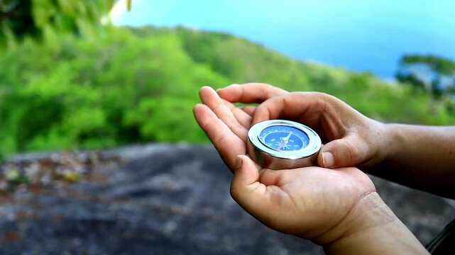 Compass in the hand on the nature background. Compass in hand on the background of the mountains and the lake. hand holds a compass against the background of the mountain and a lake.