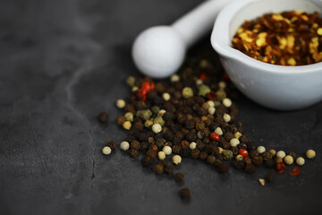 Aromatic Peppercorn and Spice Mix Overflows from White Mortar on Dark Stone Surface