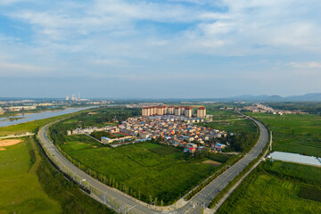 Obraz premium Suizhou City, Hubei Province, China shows a wide landscape with buildings and roads curving through green fields under a clear sky.