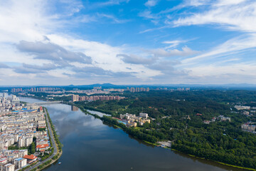 Suizhou City Hubei Province China shows buildings lining a river and green trees under a sky with clouds.