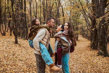 Mother and father kissing while carry daughter on their backs, piggyback ride.
