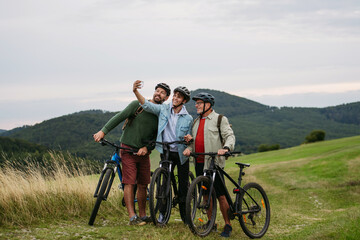 Obraz na płótnie Canvas Grandfather, father and teen boy on cycling trip taking selfie.