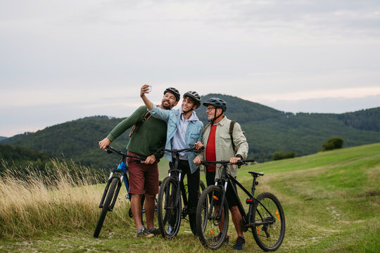 Grandfather, father and teen boy on cycling trip taking selfie. - Powered by Adobe