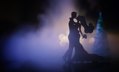 Black silhouettes of pair dancers performing. Man and woman are dancing with white backlight. Choreography. New Year's ball