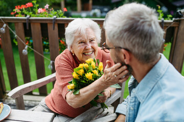 Mature son spending time with elderly mother, drinking coffee and talking.