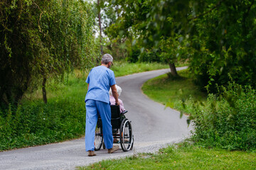 Male home nurse taking care of elderly woman in wheelchair.