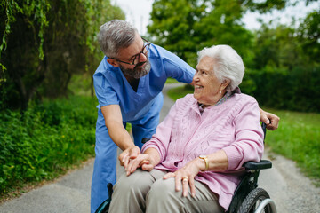 Male home nurse taking care of elderly woman in wheelchair.