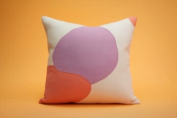 A decorative pillow, featuring abstract shapes in soft pastel colors, sits against a warm, neutral backdrop.