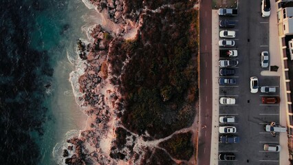 Coastal view with parked cars and rocky shoreline during late afternoon