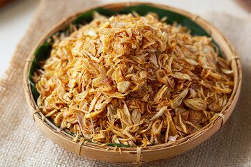 Generous serving of crispy fried shallots (bawang goreng) piled high in a traditional woven basket. These golden brown, aromatic fried onions are a beloved condiment in cuisines.