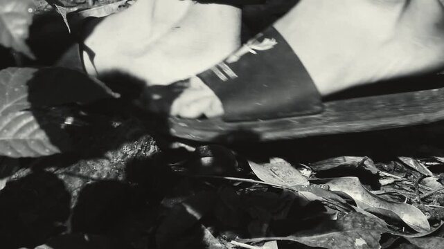 A Gritty, High-Contrast Black and White Photograph Capturing a Close-up View of a Person's Bare Feet and the Strap of a Simple Sandal or Slipper