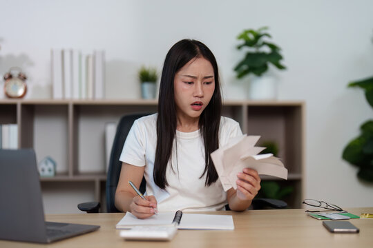Financial Management. Young woman analyzing bills and feeling frustrated at home office.
