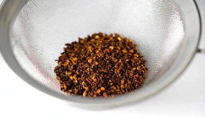 Dried spice granules in a metal strainer