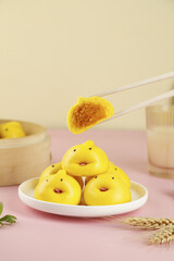 Adorable Yellow Cartoon Steamed Buns with Pumpkin Filling and Chopsticks on Pink Background