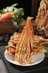 Dried bamboo shoots on plate with fresh vegetables in rustic kitchen setting