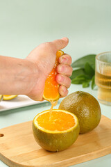 Fresh Orange Juice Hand Squeezing Citrus Fruit on Wooden Board Healthy Vitamin C Drink Preparation