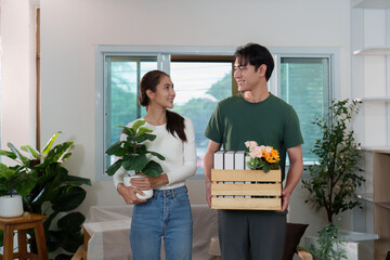 Couple Collaborating: Young Partners Carrying Plants and Boxes in New Home