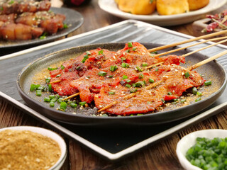 Grilled Pork Tenderloin Skewers on Cast Iron Plate with Green Onion Garnish - Asian Barbecue Cuisine