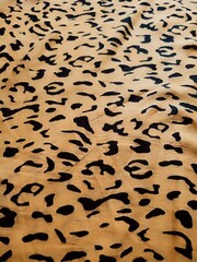 The pattern and background of the yellow fabric with black dots resembles leopard skin.