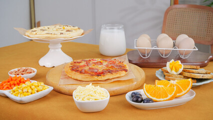 Delicious homemade Italian pizza with cheese and breakfast spread on wooden cutting board in modern kitchen