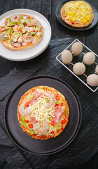 Fresh Homemade Italian Pizzas with Cheese and Ham on Rustic Kitchen Table Ready for Grilling