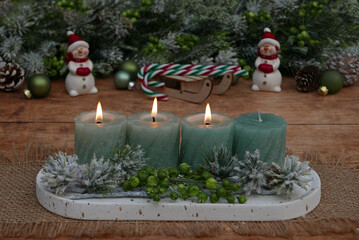 Dritter Advent: Dekoration mit grünen Kerzen, Tannenzweigen und Adventsschmuck, drei Kerzen brennen zum 3.  Advent.