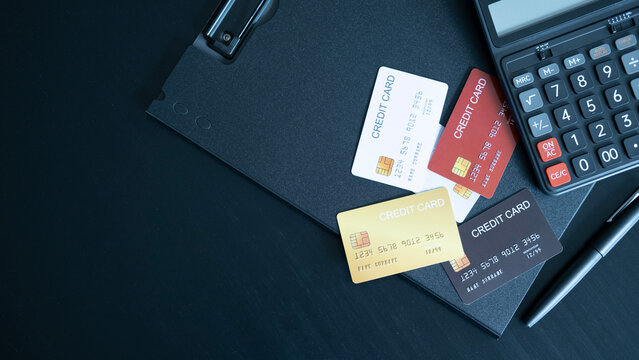 Colorful set of credit cards in red white gold and black on dark folder with calculator emphasizing variety financial identity and personal finance management.