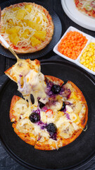 Fresh Baked Italian Pizzas with Fruit Toppings and Melted Cheese on Dark Serving Plates