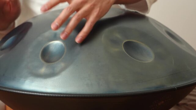 Close-up of a hand gently tapping melodies on a handpan (hang drum) in a calm indoor studio with warm natural light&mdash;great for meditation, ambient music, wellness and therapy themes.