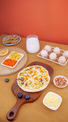 Delicious Italian pizza with cheese and beef ingredients for baking on wooden cutting board