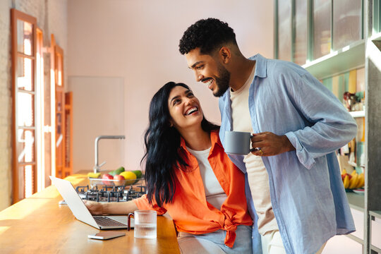 Happy couple enjoying morning coffee together in a modern kitchen setting. - Powered by Adobe