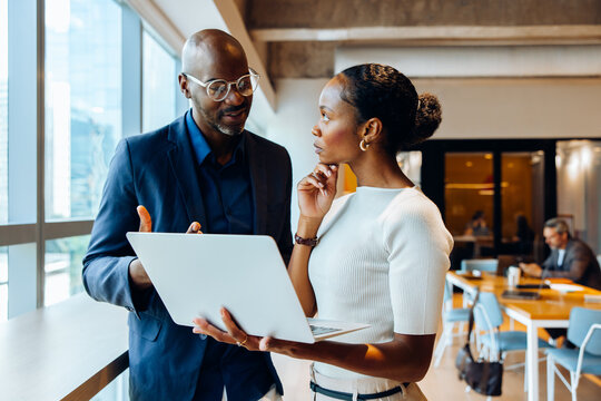Colleagues discussing a project using a laptop in an office setting