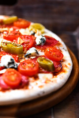 Pizza with salami, jalapeno pepper, cherry tomatoes and mozzarella cheese. Soft focus.	