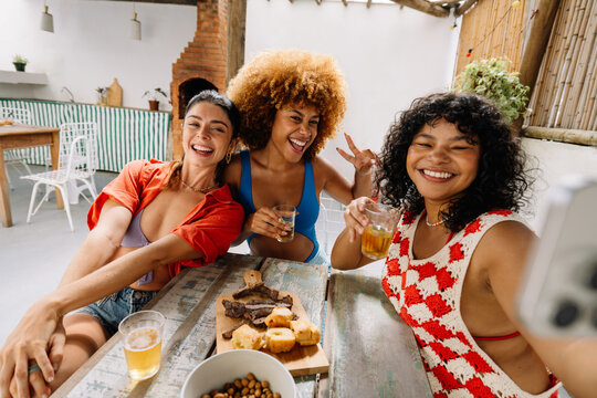 Three friends posing together while enjoying a lunch of p&atilde;o de alho and churrasco