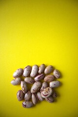 Obraz premium Scattered beans on yellow color background with copy space.