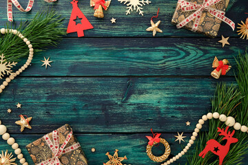 Rustic Christmas flat lay with gifts, pine branches, festive ornaments, and wooden beads on teal wood table