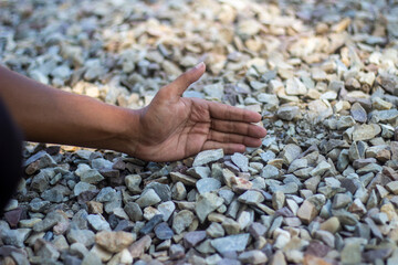 Hand resting on a bed of small, colorful gravel stones