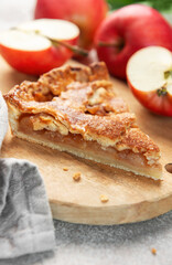 Apple pie slice on wooden board with apples