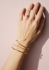 Elegant hand with jewelry rings and bracelets on a soft pink background