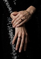 Elegant hands showcasing jewelry against a dark background with copy space