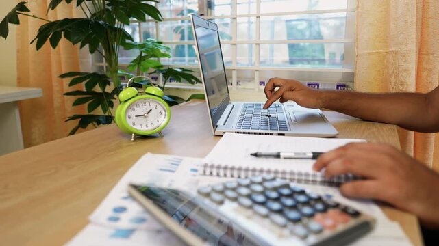 Office Workspace with Laptop and Calculator, Person working on a laptop with documents and calculator on desk