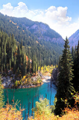 Picturesque autumn scenery of Kaindy lake with dead trees, Kolsay Lakes National Park, northern region of Tien Shan Mountains, Kazakhstan. Alpine Kaindy lake, Almaty region, Kazakhstan