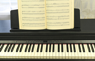 Notebook with musical scores placed on sleek electronic piano, highlighting preparation. notebook is essential for preparing flawless performance.