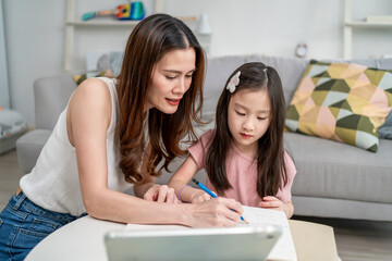 Asian loving mother support young kid daughter doing homework in house.