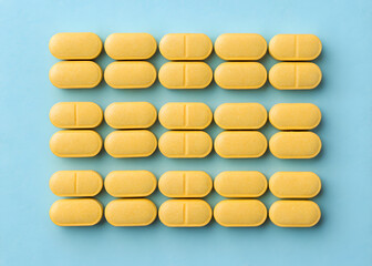 The yellow tablets arranged on a blue background for health and wellness imagery.