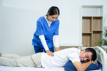 Fototapeta premium Nurse provides back massage to senior patient in clinic. Perfect for physiotherapy, rehabilitation, aging care, wellness, pain relief, and professional healthcare themes.