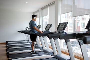 Asian young man with prosthetic leg walk on a treadmill at the gym